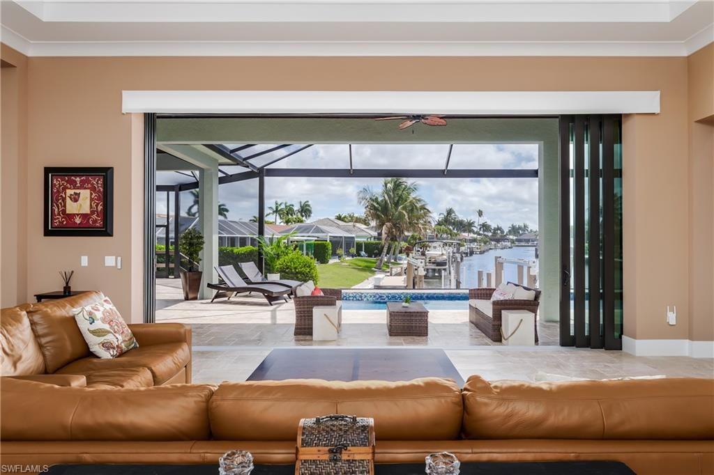 Expansive folding glass doors open to a screened lanai with a swimming pool, extending to a waterfront canal