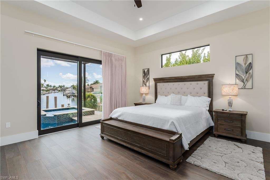 Spacious room featuring wood-finish flooring, a tray ceiling, and a transom window