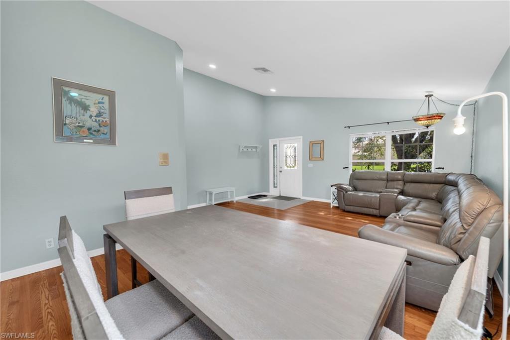 Open-concept living space featuring wood-finish flooring, recessed lighting, and vaulted ceilings