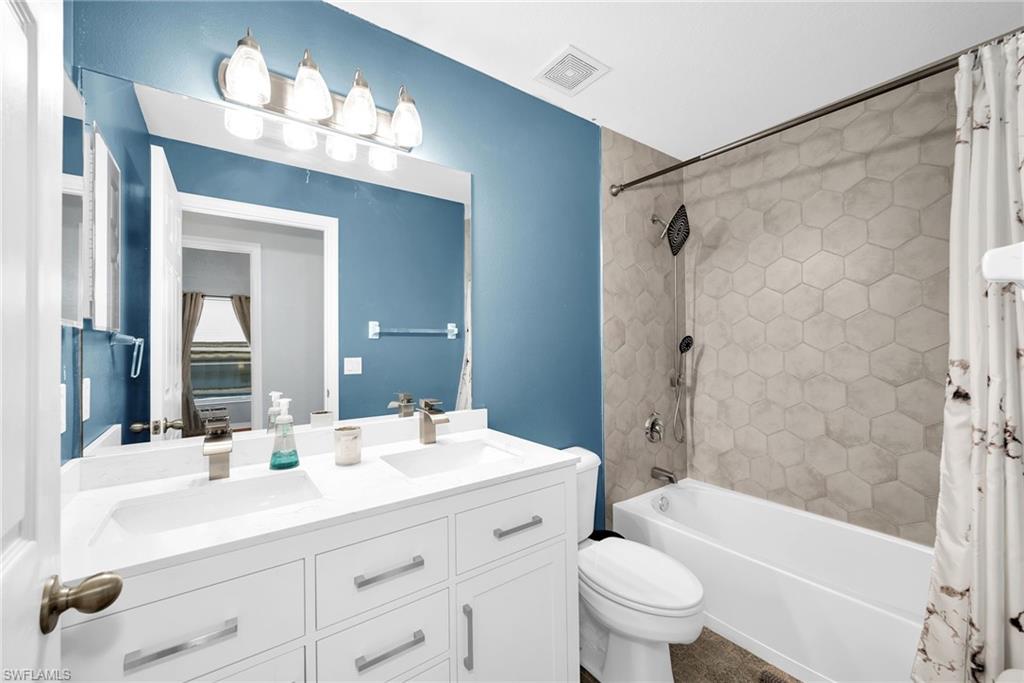 Bathroom featuring a dual vanity with white cabinetry, rectangular undermount sinks, and brushed nickel faucets