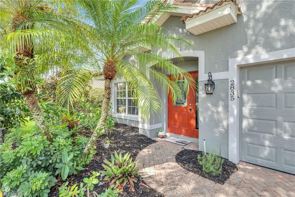 Inviting stucco exterior with a terra cotta tile roof, accented by a vibrant orange entry door with decorative glass