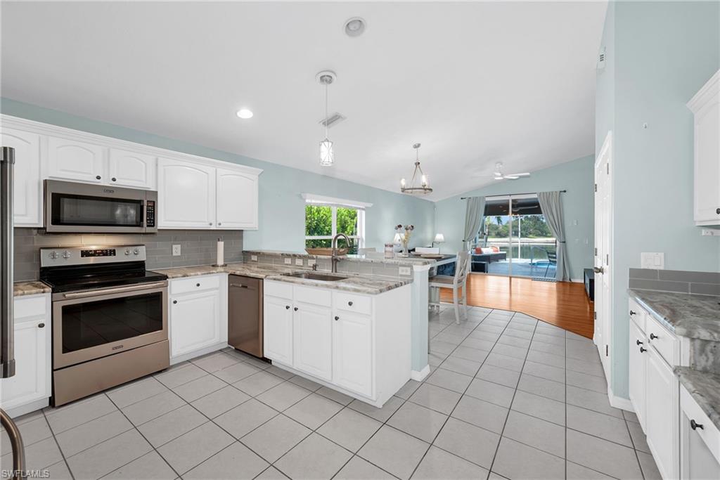 Kitchen featuring white cabinetry, stainless steel appliances, granite countertops, and a tiled backsplash