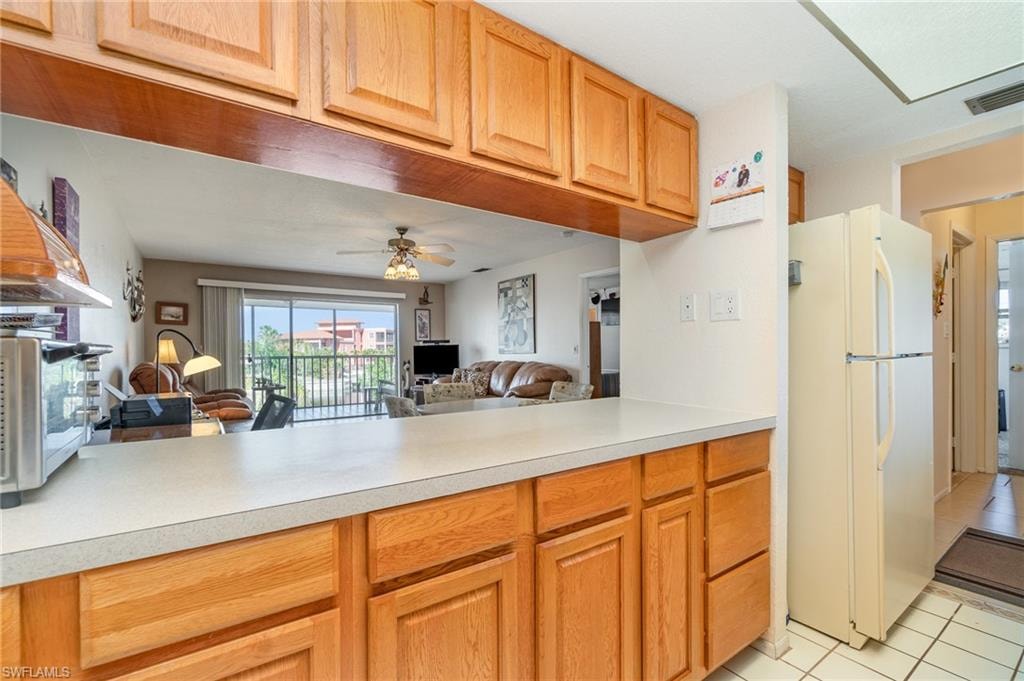 Kitchen pass-through featuring light wood-finish cabinetry, a white countertop, and a built-in refrigerator