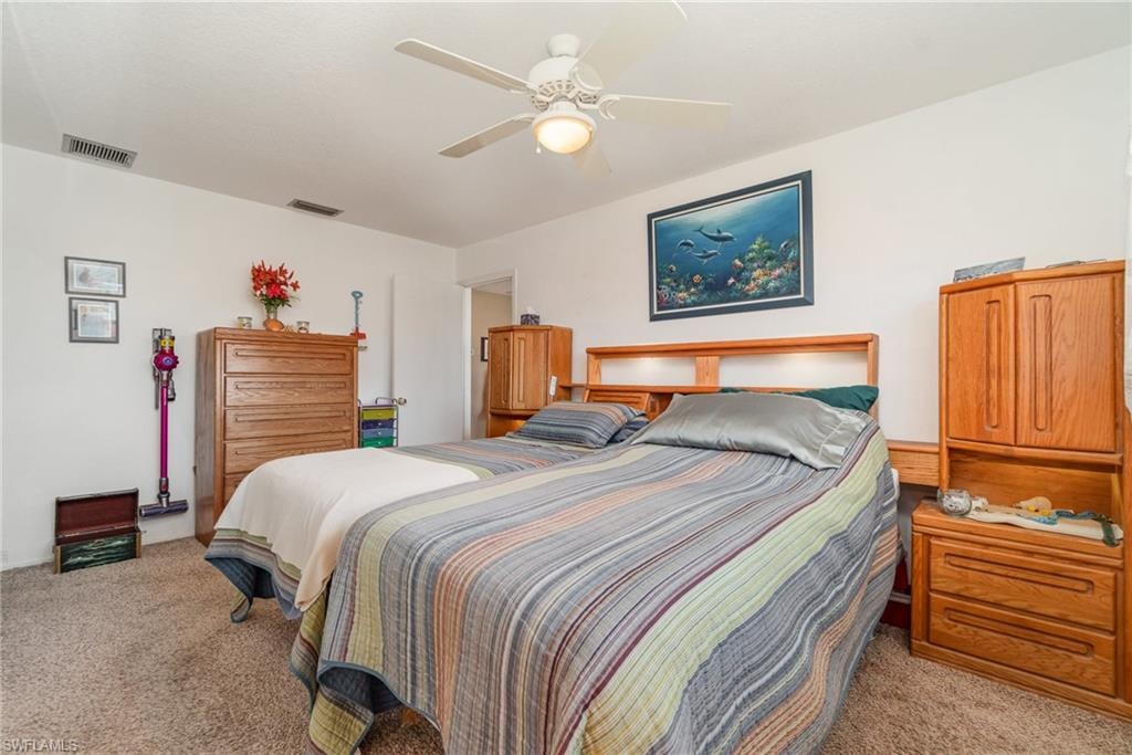 Carpeted room featuring a ceiling fan with integrated lighting, white walls, and an arched doorway