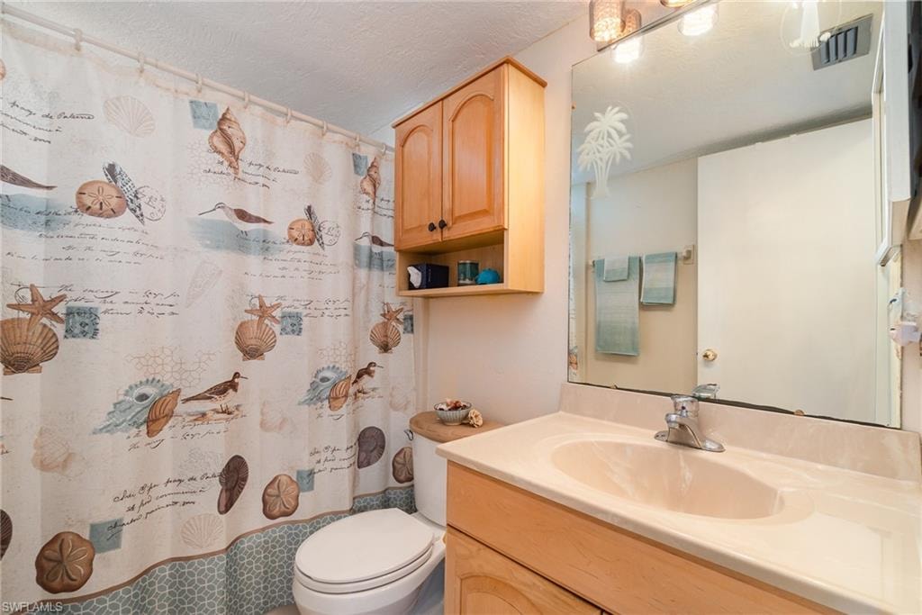 Bathroom featuring a vanity with an integrated sink, a large wall-mounted mirror, and a wall-mounted wood-finish cabinet with open shelving