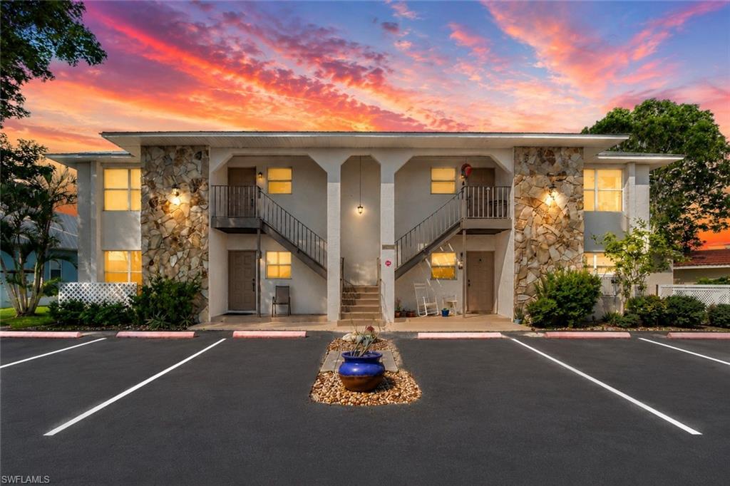Two-story stucco building featuring decorative stone veneer accents, multiple entry doors, and external staircases leading to upper-level units
