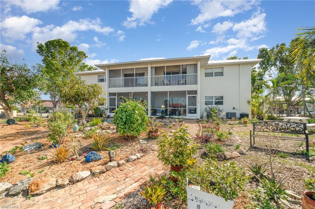 Two-story white exterior building featuring a screened-in lower patio and an upper screened balcony