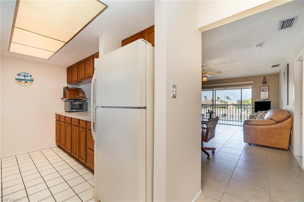 Kitchen featuring wood cabinetry, white appliances, and a rectangular ceiling light fixture