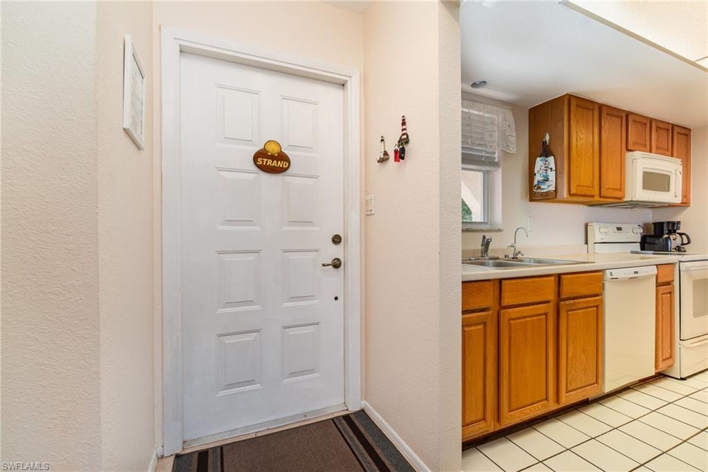 Kitchen featuring wood-finish cabinetry, white appliances, and a tile floor