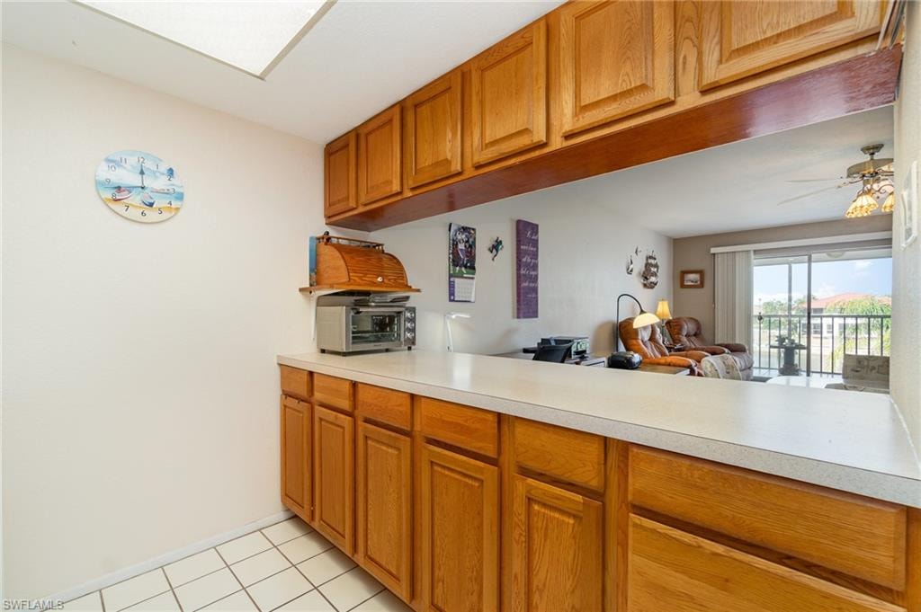 Kitchen pass-through featuring light wood-finish cabinetry, white countertop, and tile flooring