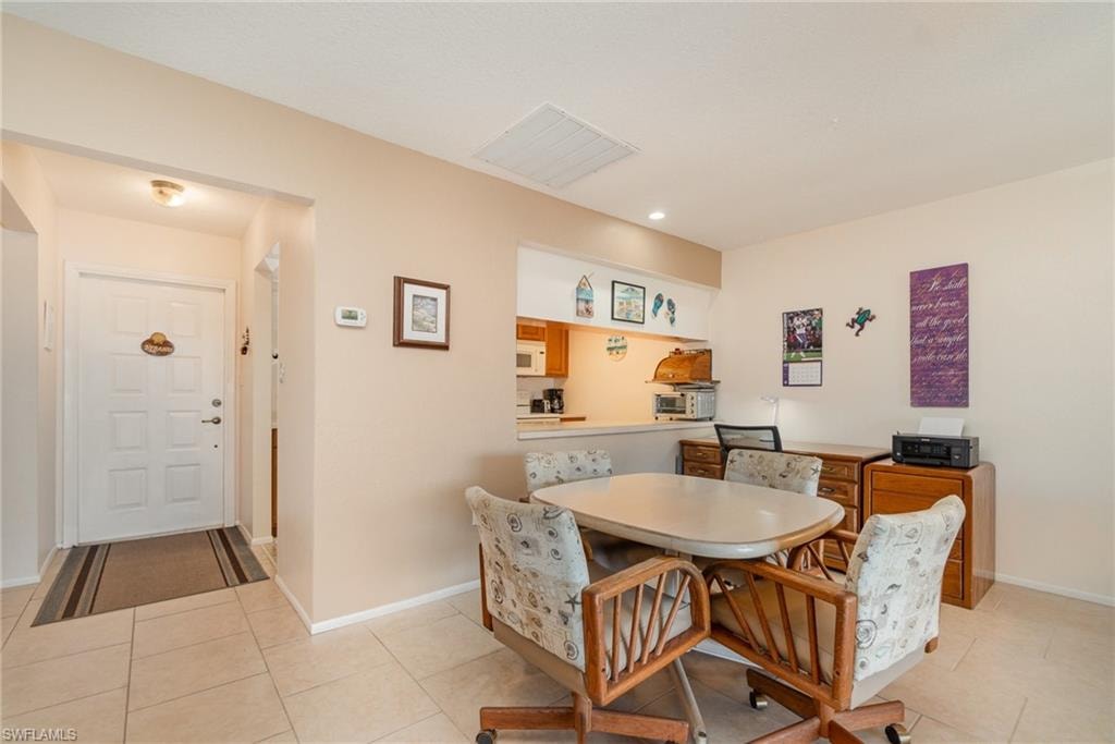 Tiled entry foyer with a paneled door, flush-mount lighting, and a kitchen pass-through