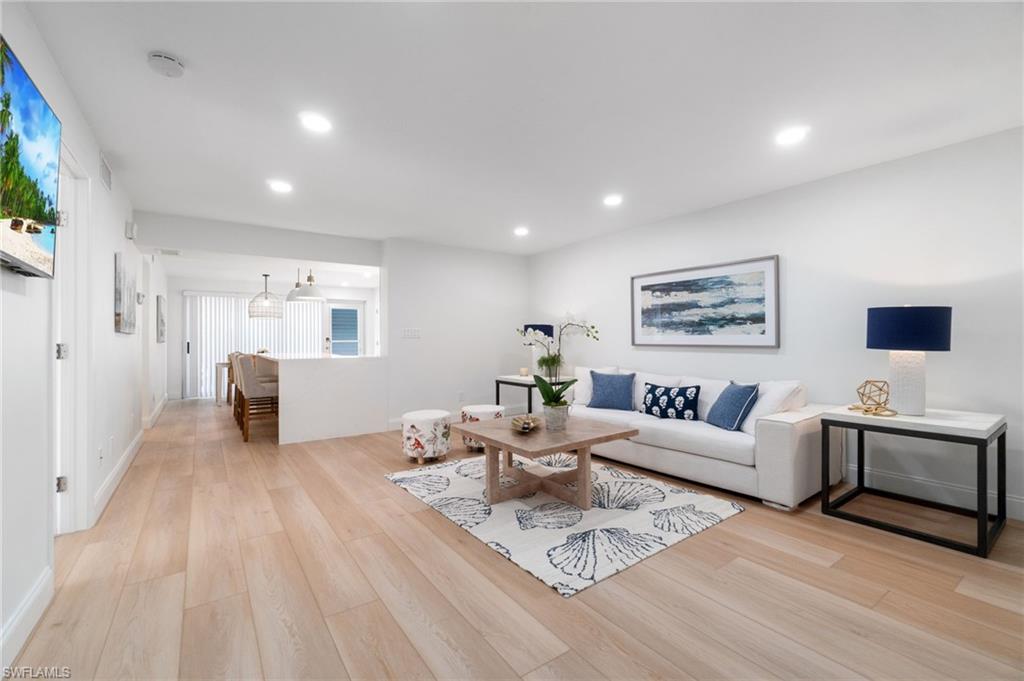 Open-concept living space featuring light wood-finish flooring, recessed lighting, and crisp white walls