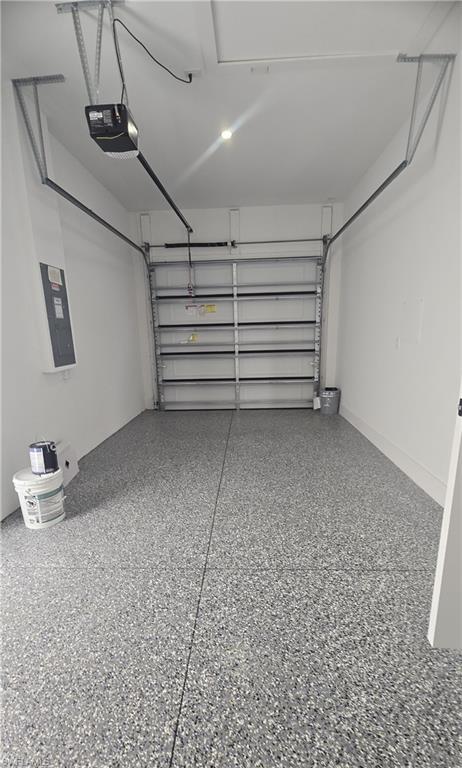 Garage interior featuring a speckled epoxy floor coating, white painted walls, and a visible garage door opener mechanism