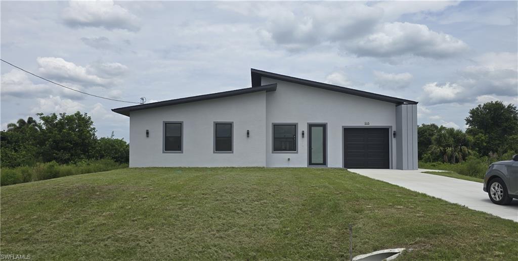 Contemporary single-story residence with a gray stucco exterior and dark trim windows