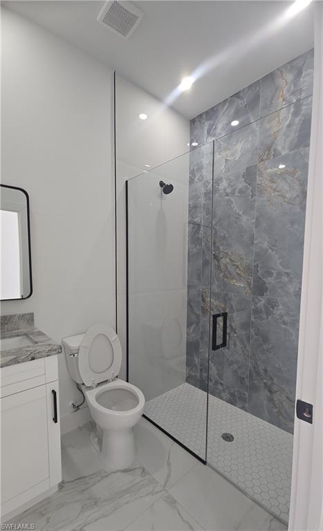 Walk-in shower featuring gray veined wall tiles, a hexagon tile floor, and a black-framed glass enclosure