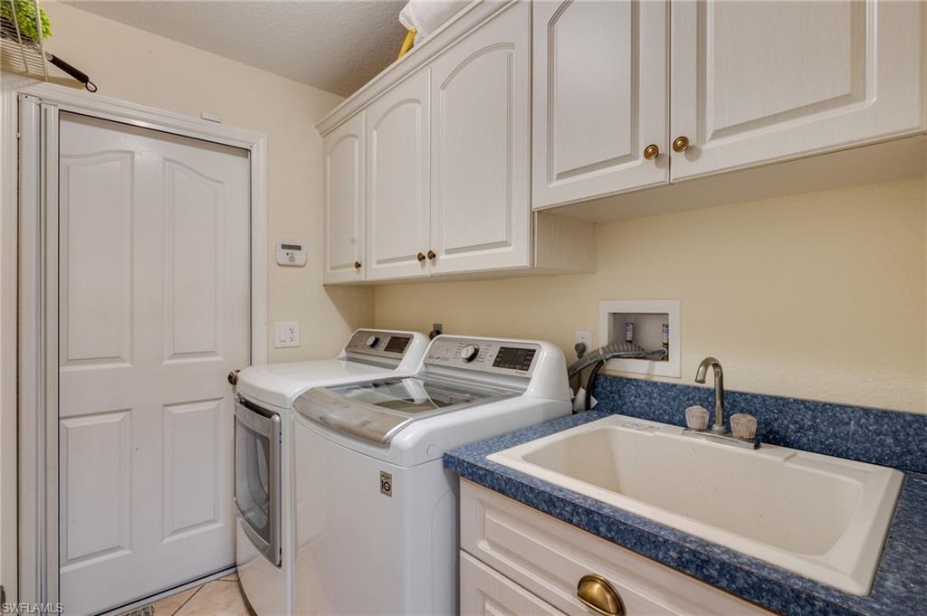 Laundry area off the kitchen with sink and screen door opening to the 2 car garage.