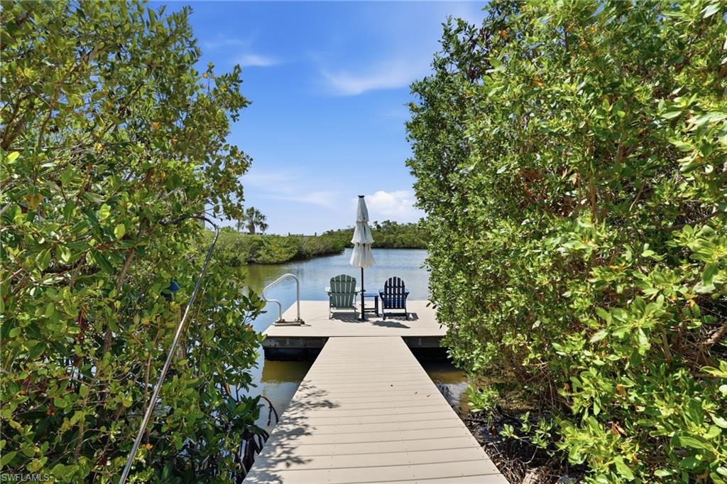 Waterfront property featuring a composite wood dock, natural waterway access, and lush surrounding foliage - Virtually Edited Image