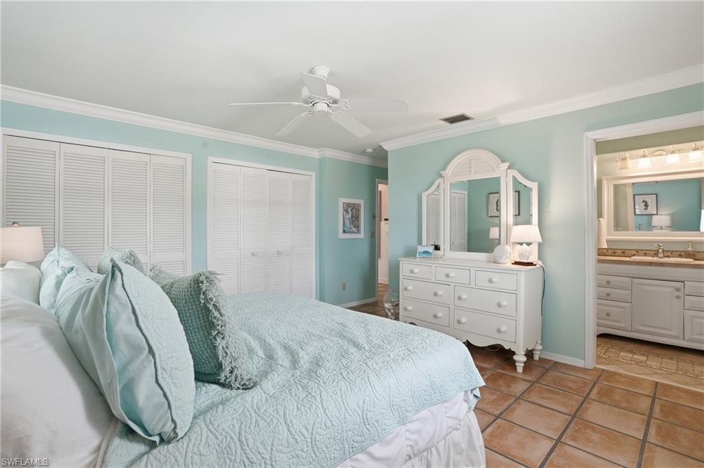Spacious room featuring a white ceiling fan, crown molding, and two sets of louvered bi-fold closet doors - Virtually Edited Image