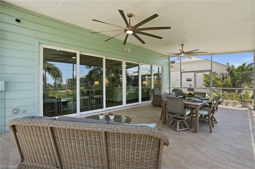 Screened lanai featuring large format tile flooring, multiple ceiling fans, horizontal siding, and multi-panel sliding glass doors - Virtually Edited Image