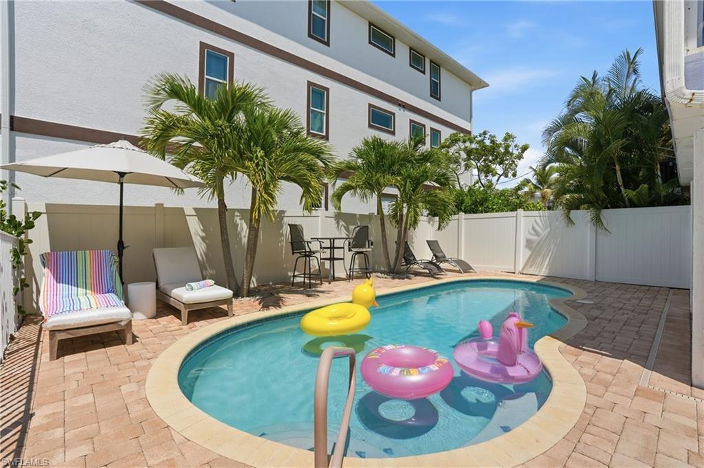 Private outdoor space featuring a freeform swimming pool with integrated steps, surrounded by paver patio decking - Virtually Edited Image