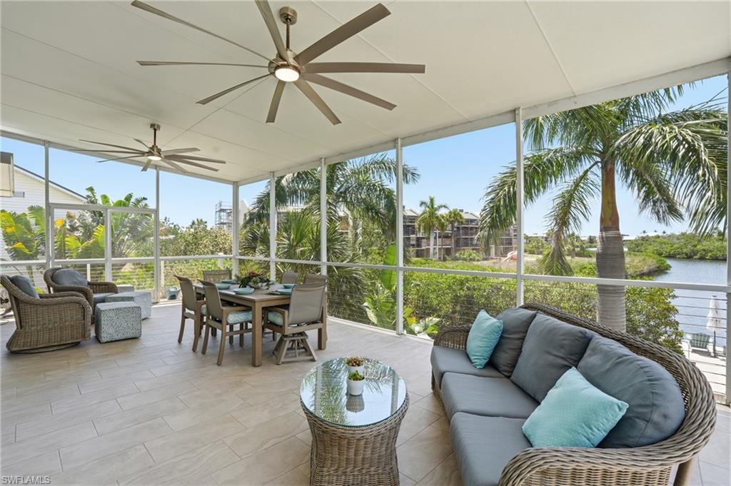 Spacious screened lanai featuring large format tile flooring and multiple ceiling fans - Virtually Edited Image