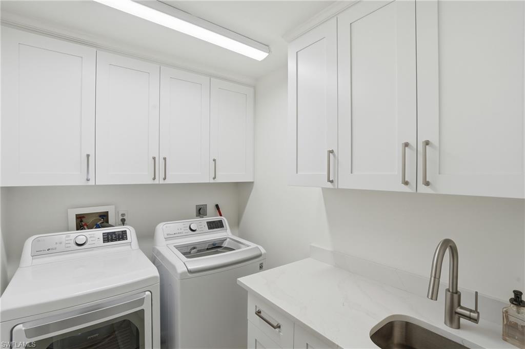 Laundry area featuring white shaker-style cabinetry, a white countertop with an integrated sink, a brushed nickel faucet, and overhead linear lighting - Virtually Edited Image