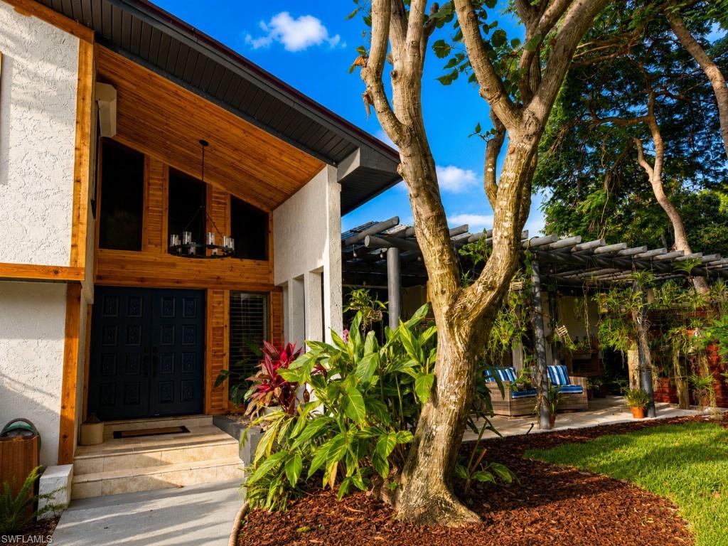 Modern architectural facade featuring a prominent wood-finish entry, a double door entrance, and an overhead chandelier