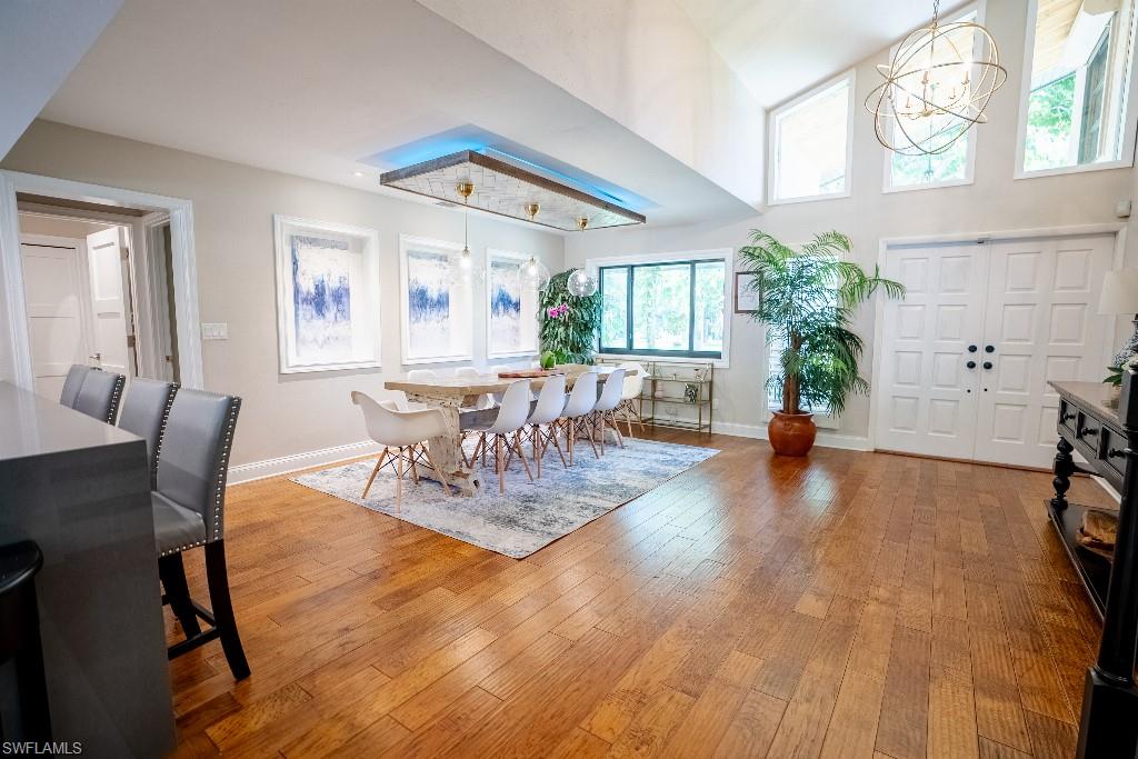 Expansive open-concept living area featuring rich wood-finish flooring, a vaulted ceiling, and multiple high-set windows