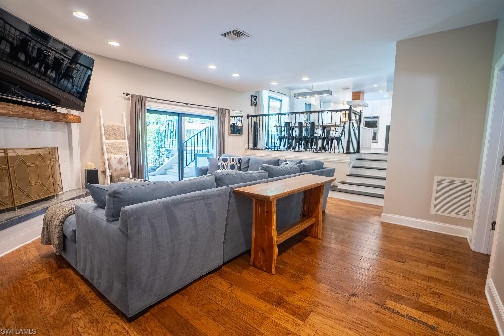 Spacious living area featuring wood-finish flooring, a fireplace with a wood mantle and tile surround, and recessed lighting