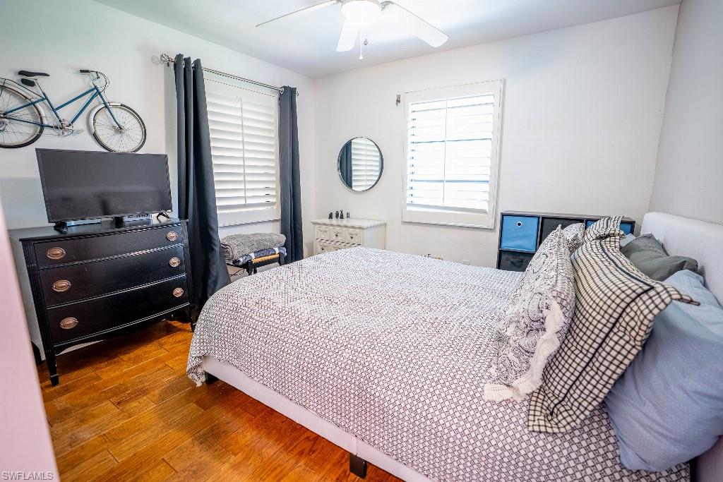 Room featuring wood-finish flooring, a ceiling fan, and window with plantation shutters