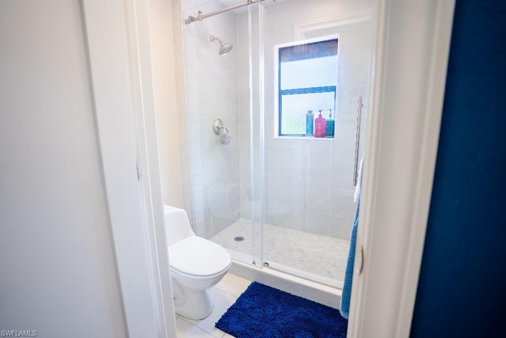 Walk-in shower featuring a glass enclosure, white subway tile surround, recessed window, and polished chrome fixtures