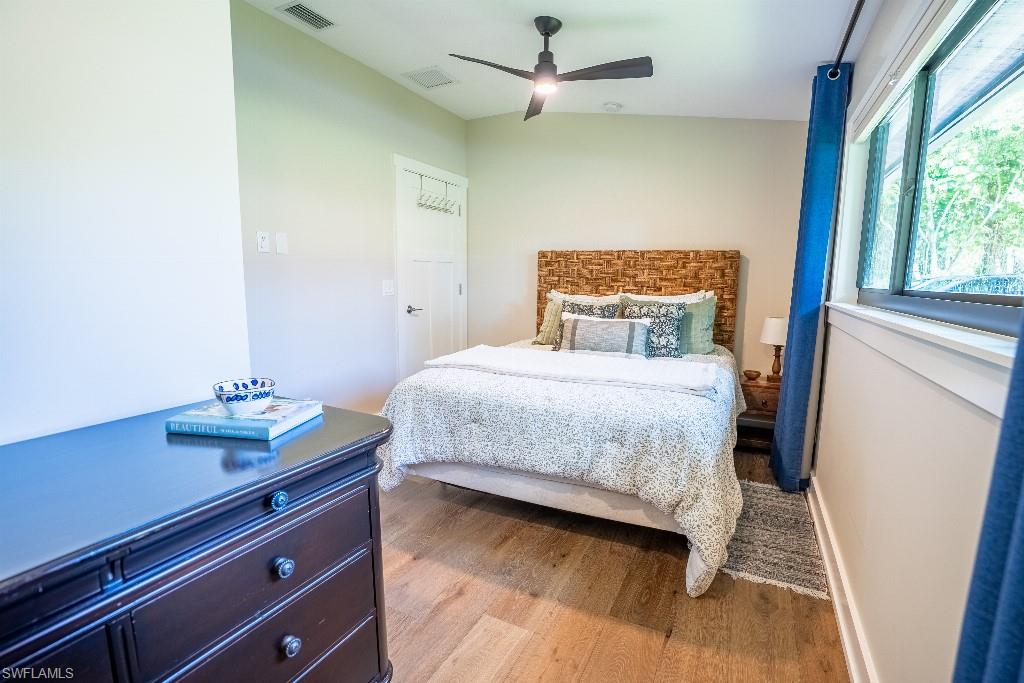 Room featuring wood-finish flooring, a contemporary ceiling fan, and large windows with blue drapery