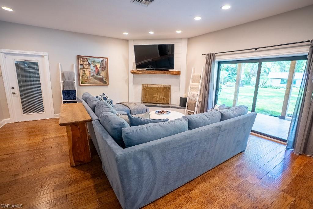 Living area featuring wood-finish flooring, recessed lighting, and a corner fireplace with a rustic wood mantel