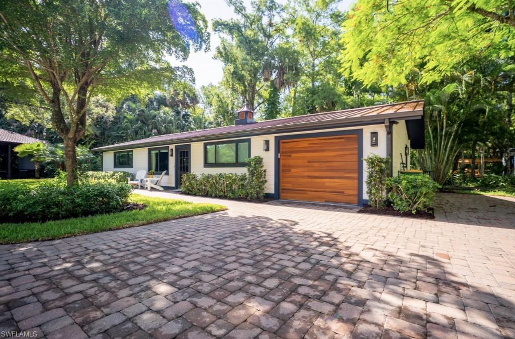 Contemporary exterior featuring a wood-finish garage door, white siding, and dark trim