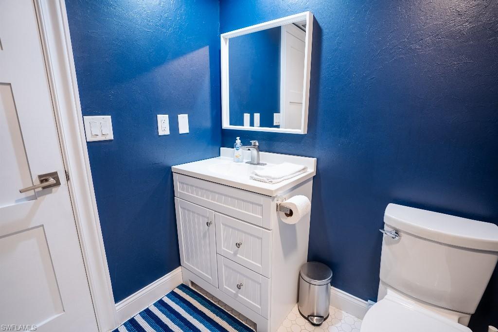 Bathroom featuring a white vanity with beadboard paneling, an integrated sink, and a framed mirror