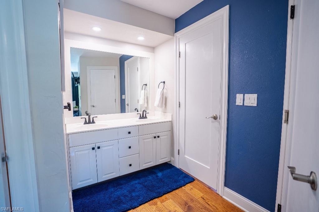 Bathroom featuring a double vanity with white cabinetry, matte black fixtures, and a spacious mirror