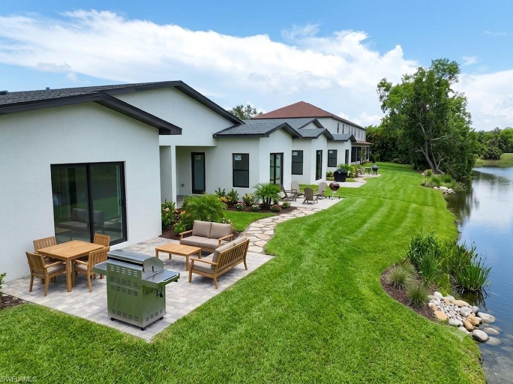Expansive green space with waterfront access, multiple paver patios, and mature landscaping