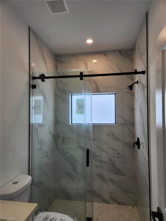 Shower enclosure with glass sliding door and black hardware, tiled walls, recessed lighting, and a frosted window