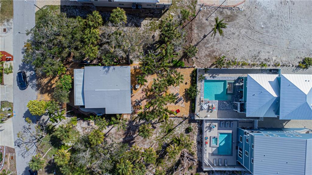 Aerial perspective showcasing multiple properties, including two with private swimming pools and surrounding paved patio areas - Virtually Edited Image