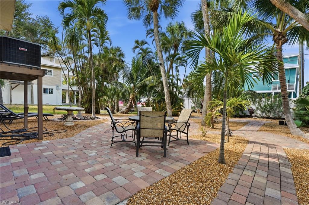 Paver patio and walkways surrounded by mature palm trees and gravel landscaping - Virtually Edited Image