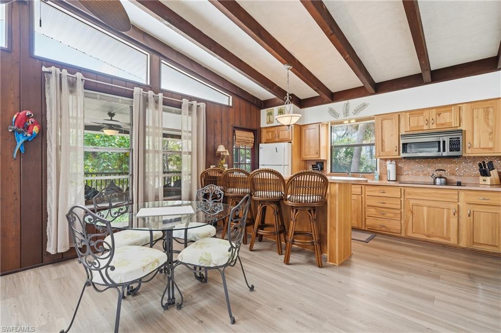 Kitchen with light wood-finish cabinetry, a stainless steel microwave, and wood-finish flooring - Virtually Edited Image