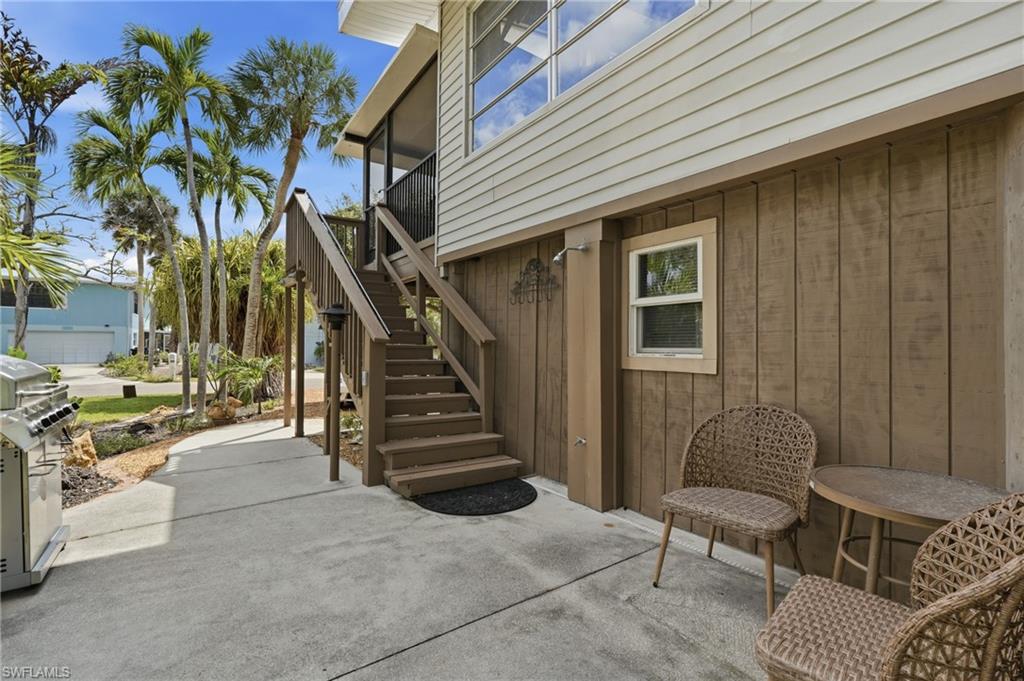 Ground-level concrete patio with an exterior staircase leading to the upper level - Virtually Edited Image