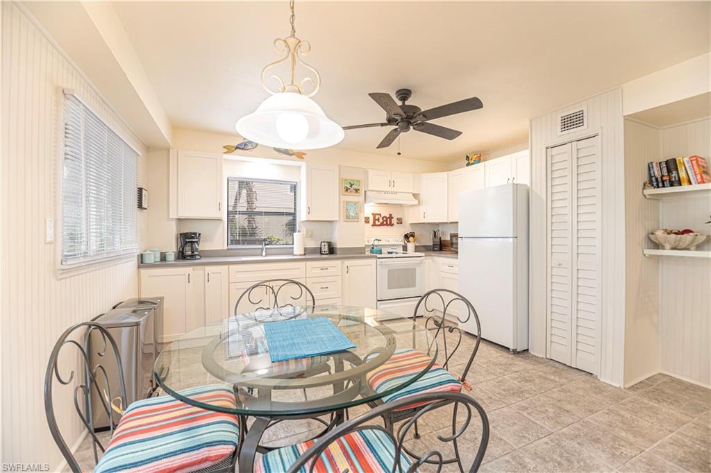 Kitchen with white cabinetry, tile flooring, a ceiling fan, and a window with blinds - Virtually Edited Image