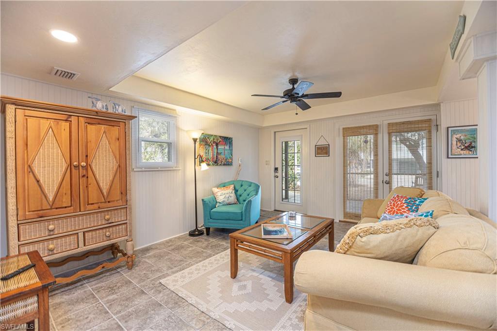Recessed lighting illuminates this room featuring tile flooring, white vertical plank walls, and a ceiling fan - Virtually Edited Image