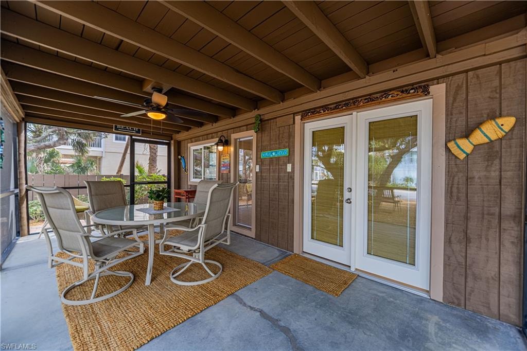 Screened patio featuring a wood-panel ceiling, concrete flooring, and a ceiling fan with integrated lighting - Virtually Edited Image