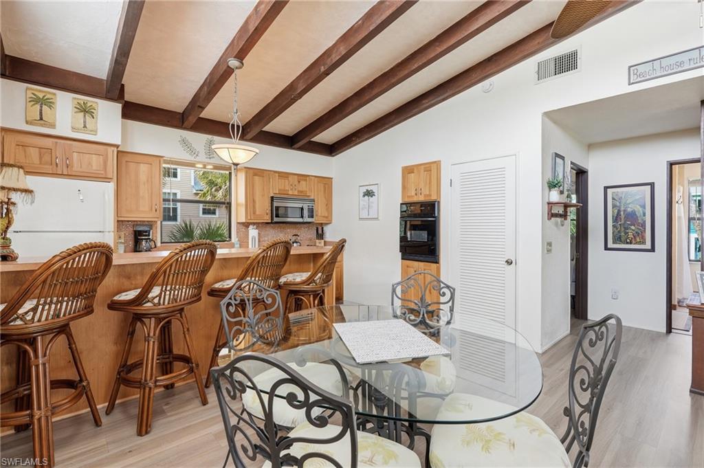 Kitchen featuring wood-finish cabinetry, a breakfast bar, and a built-in microwave - Virtually Edited Image