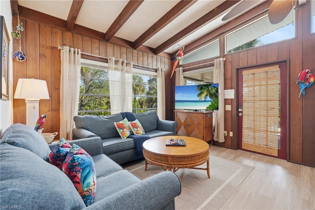 Living area featuring wood-paneled walls and a vaulted ceiling with exposed beams - Virtually Edited Image