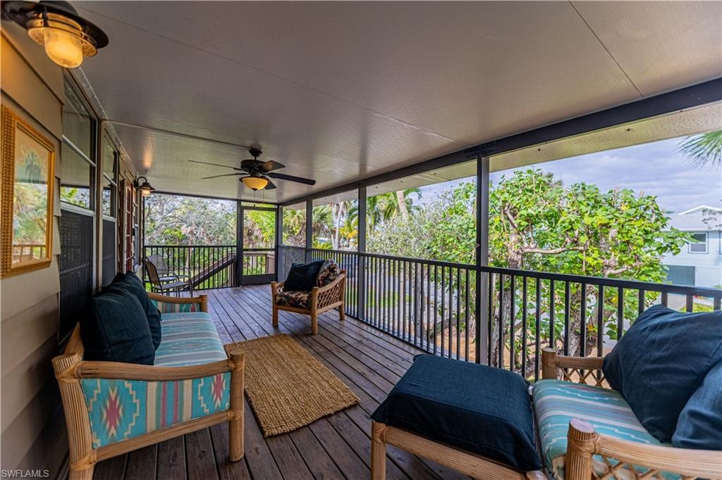 Screened outdoor living area featuring wood-finish flooring, a dark wood-finish ceiling fan with integrated lighting, and multiple wall-mounted light fixtures - Virtually Edited Image