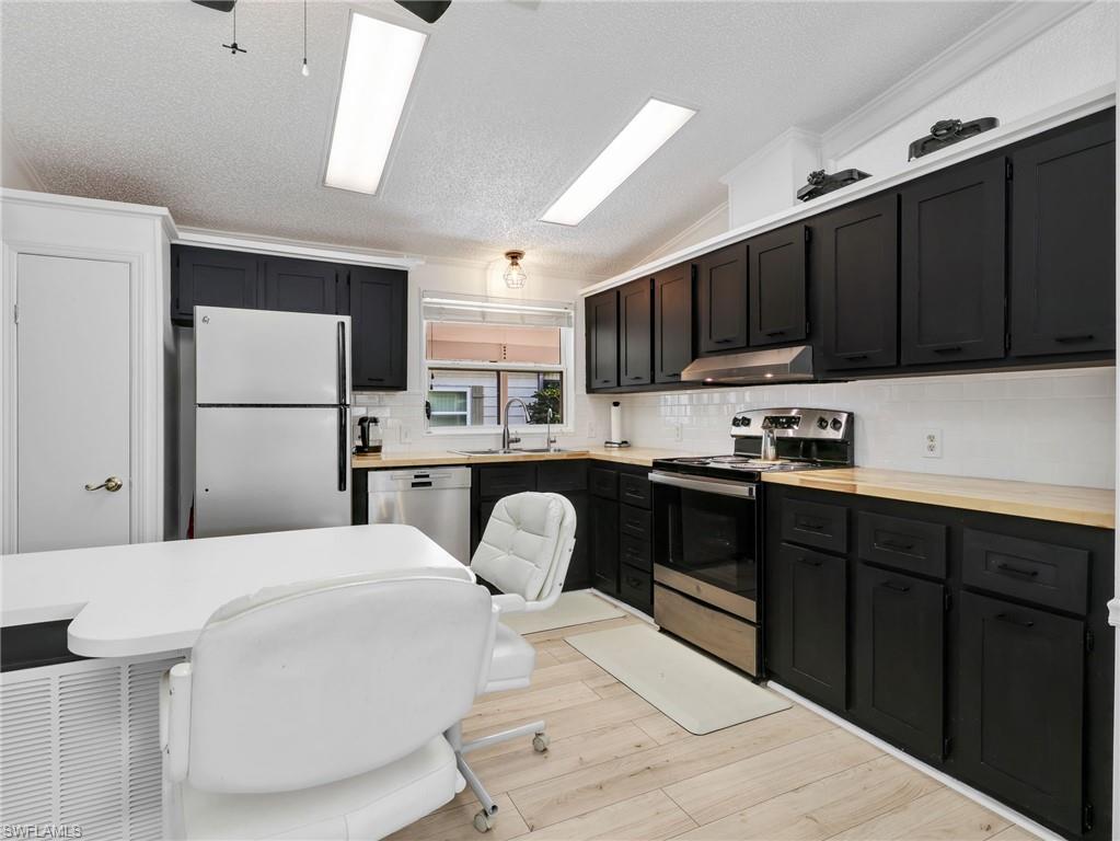 Contemporary kitchen featuring black cabinetry, light wood-finish countertops, and a white subway tile backsplash