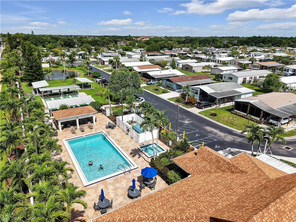 Community recreational area featuring a rectangular swimming pool, adjacent spa, covered patio, and shuffleboard courts